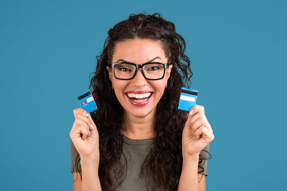 Happy debt free woman in glasses holding a credit card cut in two pieces