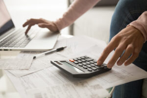 young woman calculating monthly expenses, managing budget - Prudent Financial Solutions