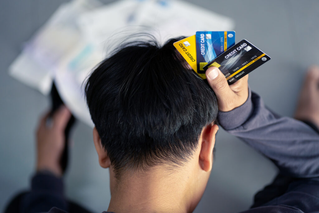 Sad confused and stressed young man holding credit cards - Prudent Financial Solutions