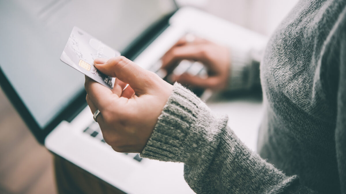 Hands holding plastic credit card and using laptop - Prudent Financial Solution