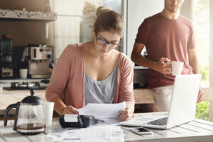 female in glasses holding piece of paper and making necessary calculations - Prudent Financial Solutions