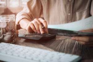 person using a calculator to compute debt and thinking how to get out of it